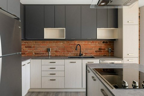 a kitchen with white cabinets and a brick wall